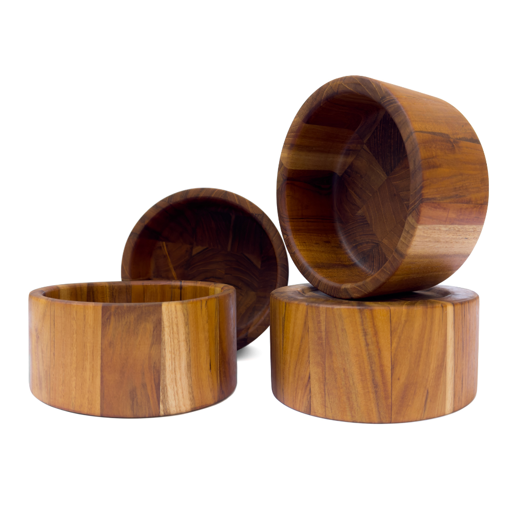 Set of four round teakwood serving bowls with natural grain patterns isolated on a white background.