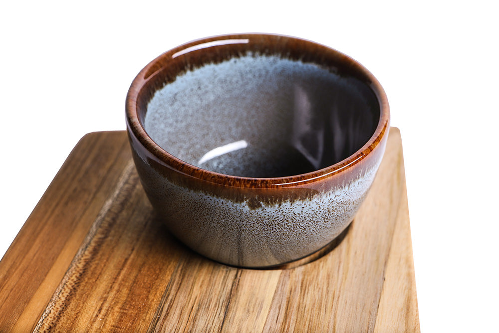 Teakhaus teakwood Geo Trapeze serving board featuring a recessed cutout and a glazed ceramic bowl.