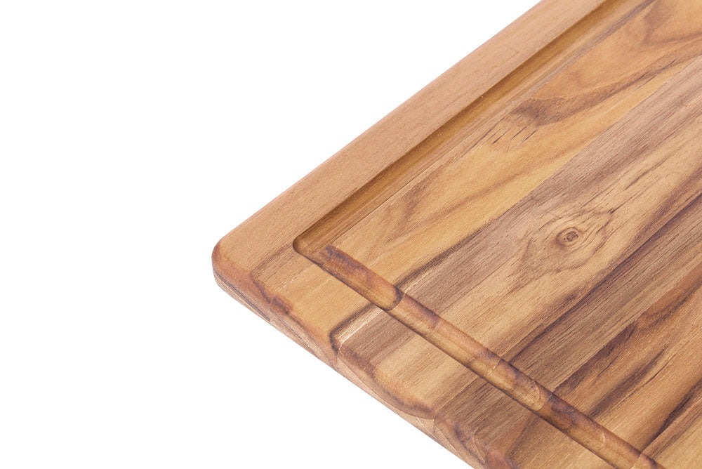 Teakwood cutting board corner highlighting the deep juice canal and natural edge grain texture.