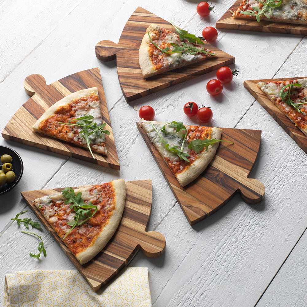 Six triangle teakwood pizza platters with individual slices and tomatoes on a rustic white wood surface.