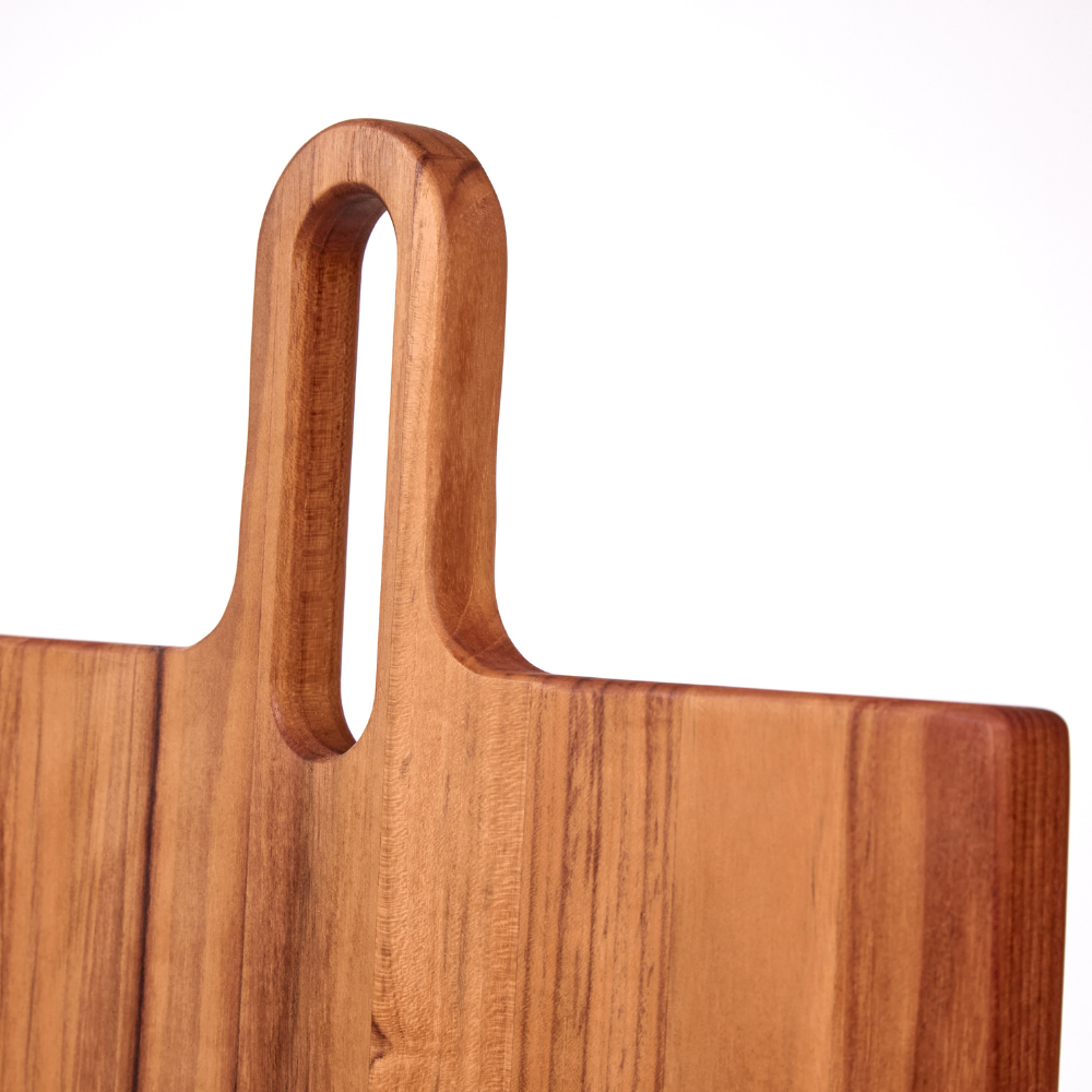 Detail of the elongated handle and natural wood grain on a square teakwood Lagom serving board.