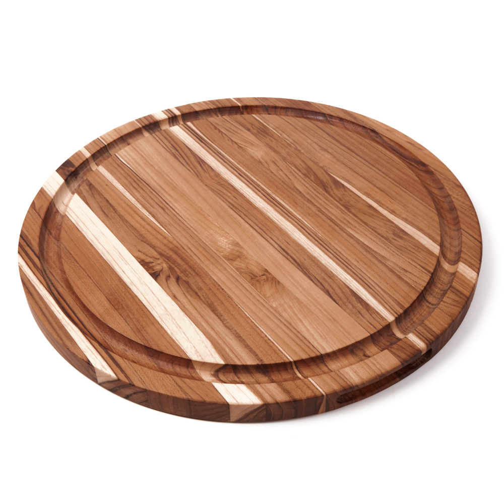Round edge grain teakwood carving board with a built-in juice groove, isolated on a white background.