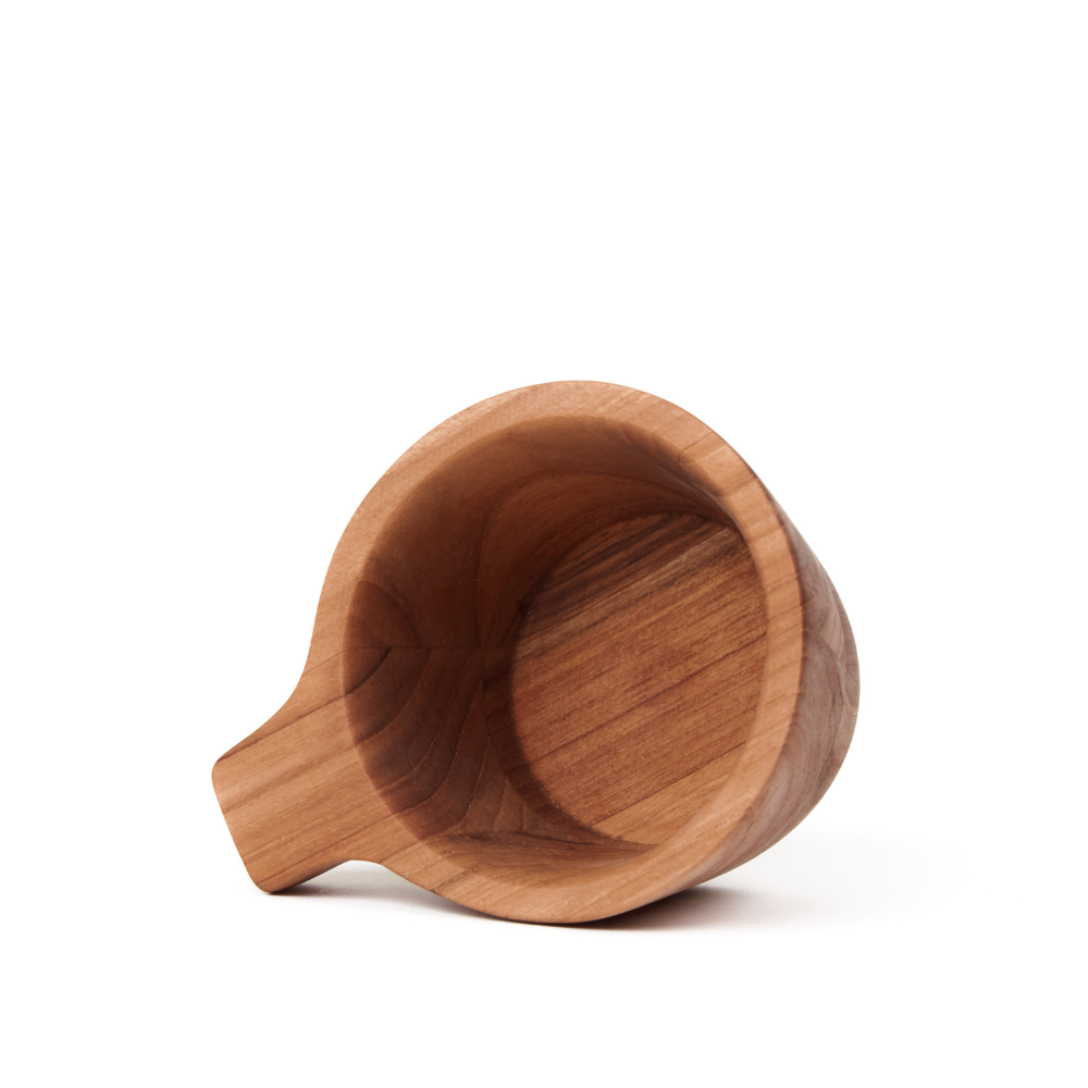 Small teakwood tapas bowl with a handle, featuring rich wood grain and tilted on a white background.