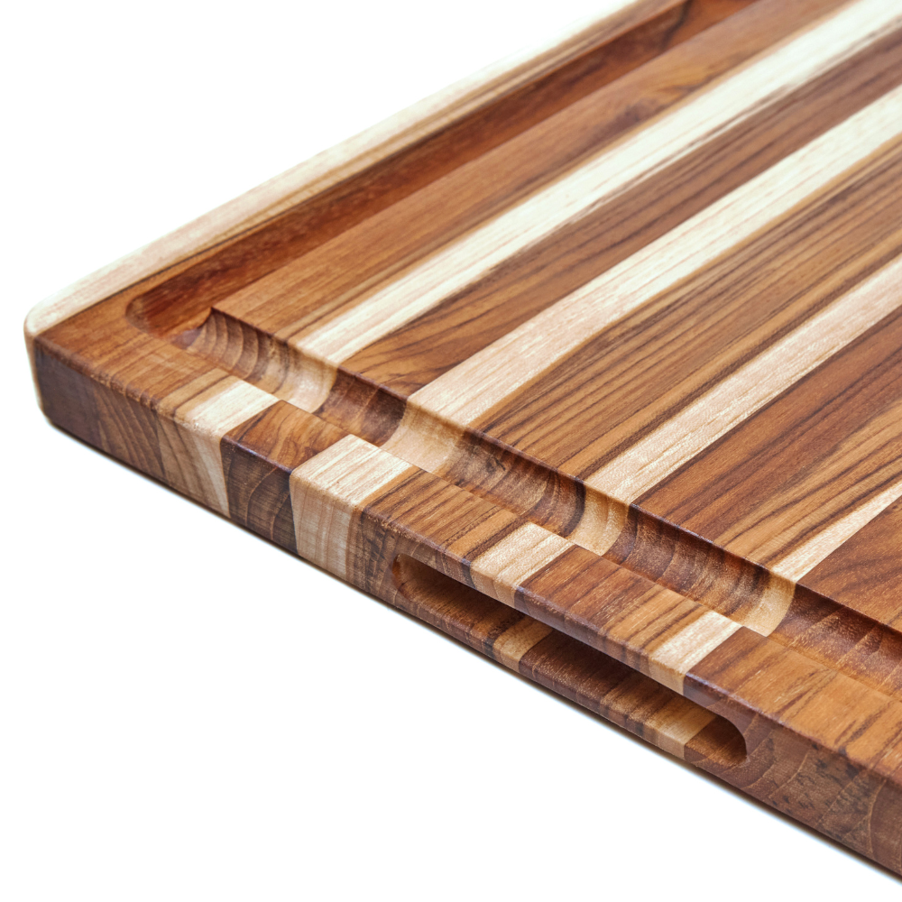 Close-up of an edge grain teakwood BBQ board featuring a deep juice canal and integrated handgrip.
