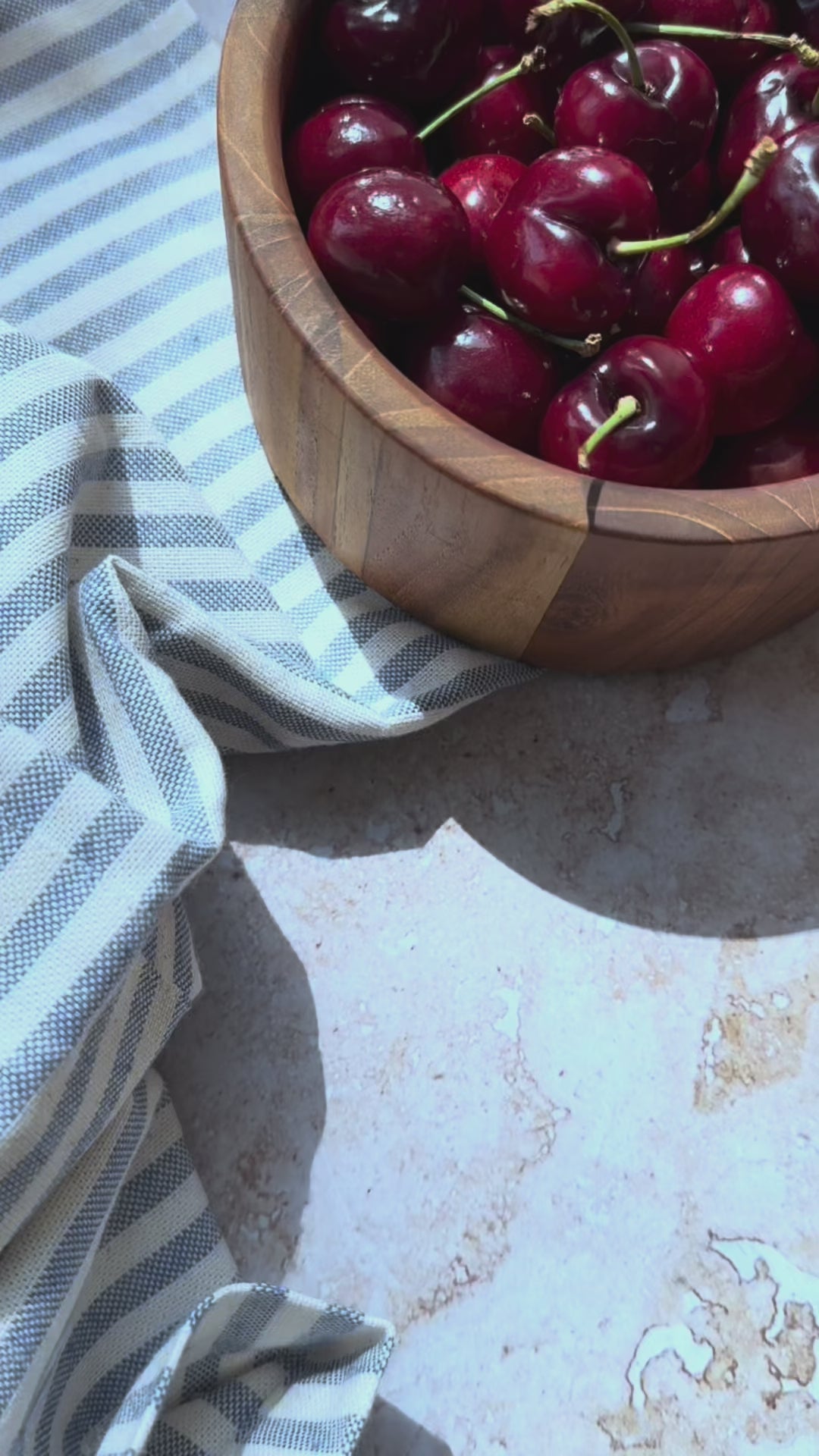 Set of four small teakwood serving bowls filled with fresh cherries, strawberries, blackberries, and green grapes.