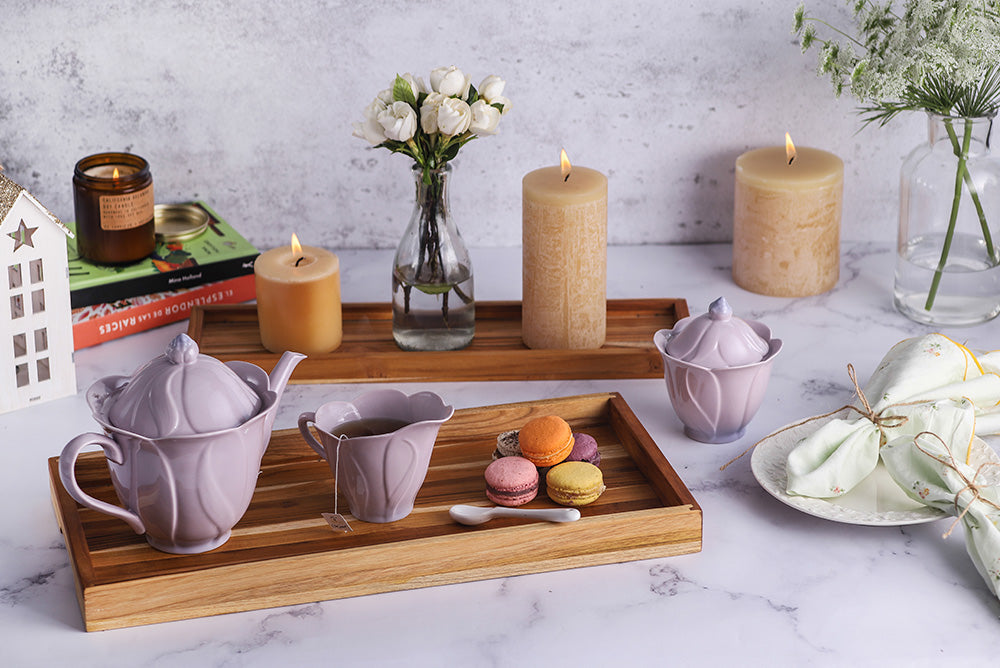 Two teakwood nesting trays styled with a purple tea set and colorful macarons in a cozy home setting.