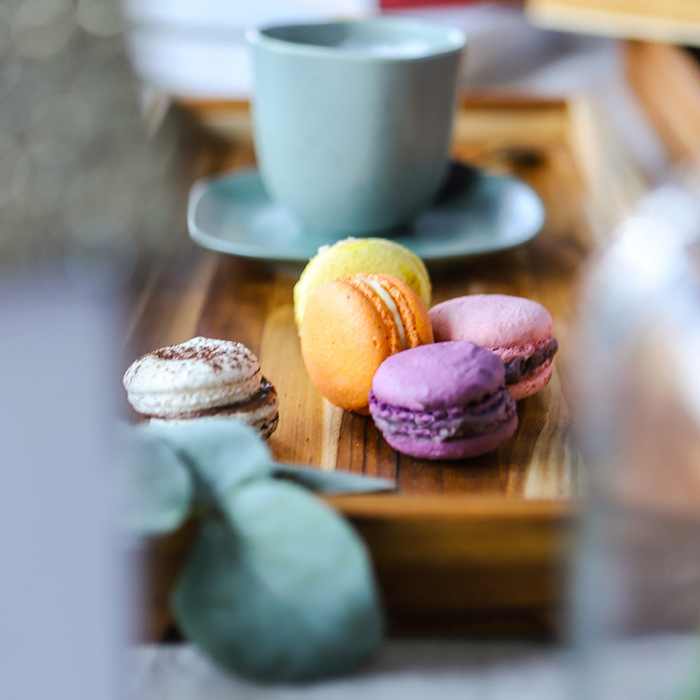 Nesting Timeless Teakwood Tray served with colorful macarons and a coffee cup in a cozy setting.