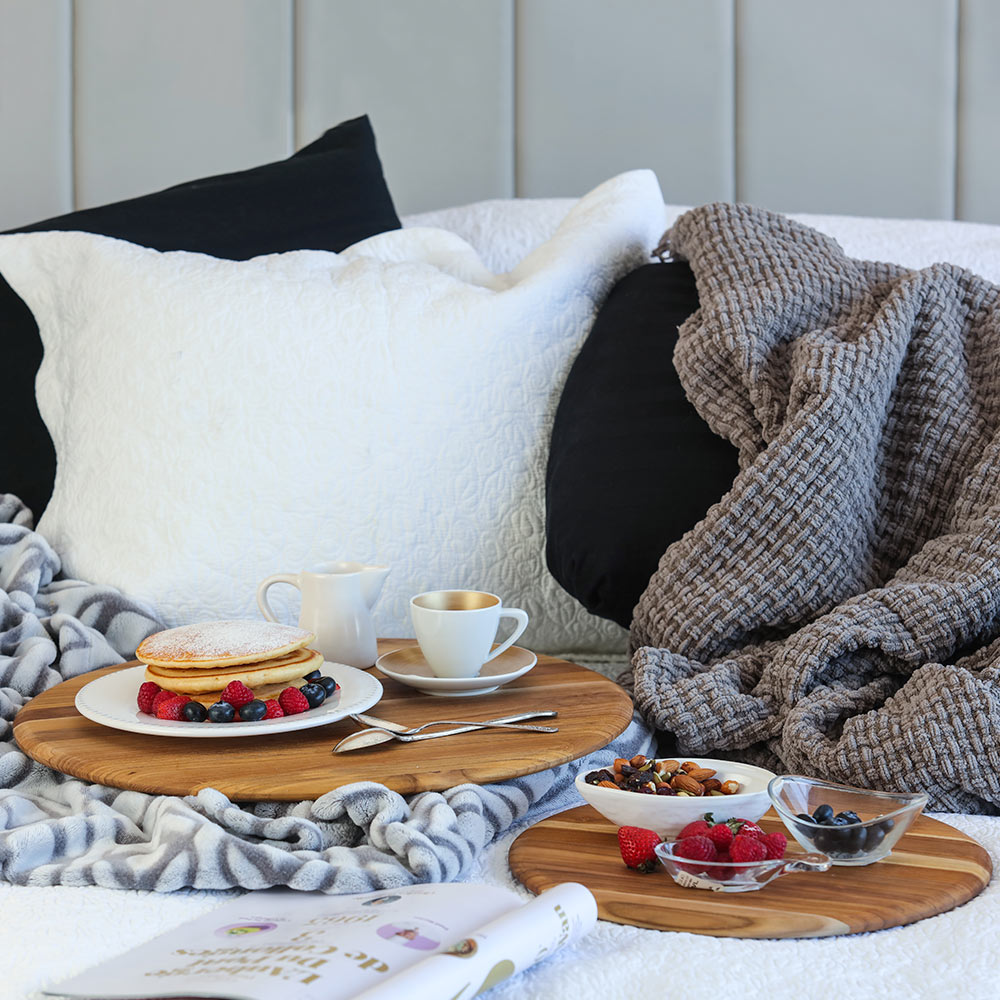 Round teakwood cutting boards with rounded edges used as trays for breakfast in bed.