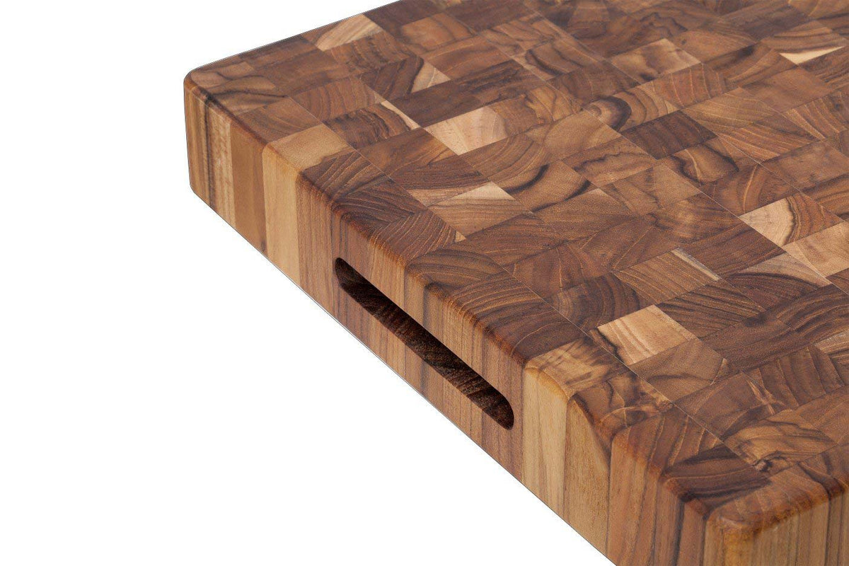 Thick square teakwood butcher block cutting board with end grain pattern and recessed hand grip.