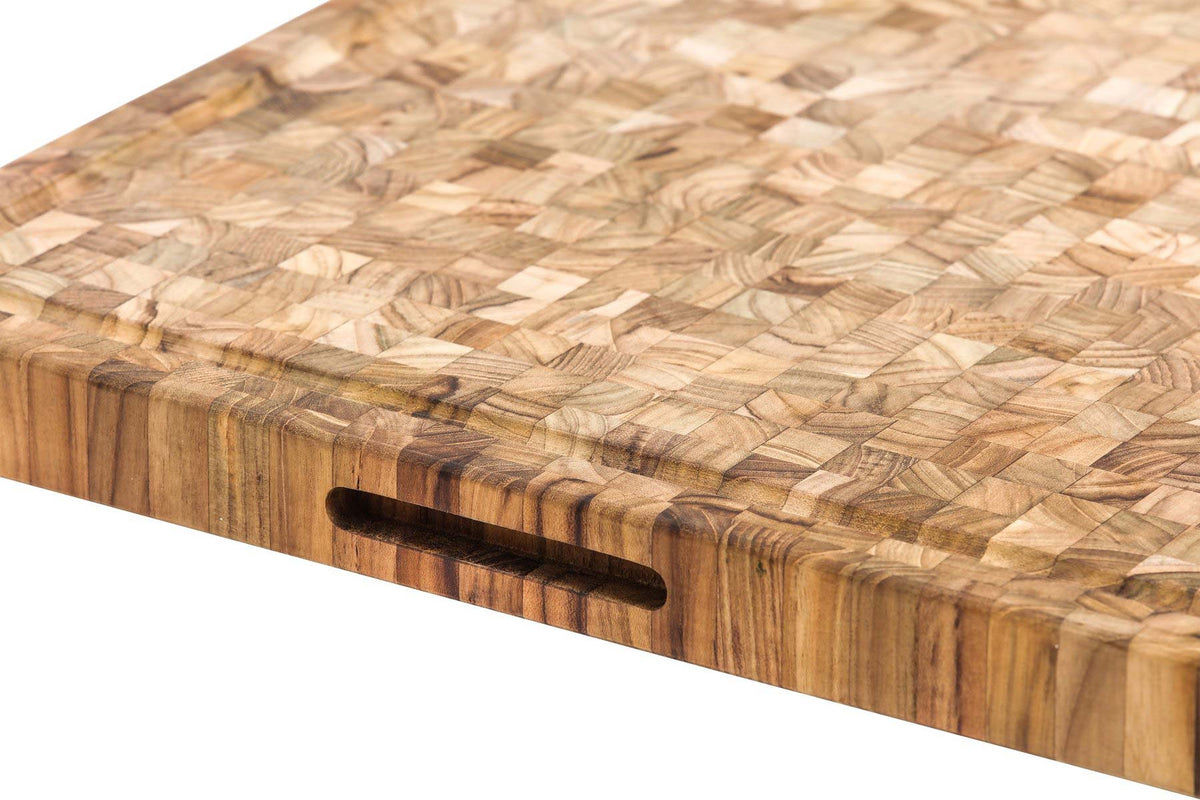 Heavy-duty end grain teakwood butcher block featuring a deep juice canal and integrated side hand grip.