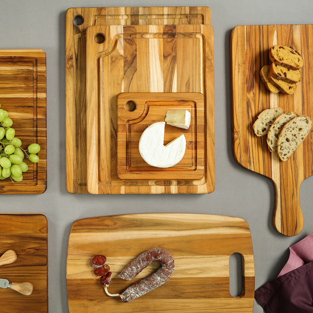 Teakwood Marine cutting boards with juice canals and corner holes, displayed with bread and cheese.