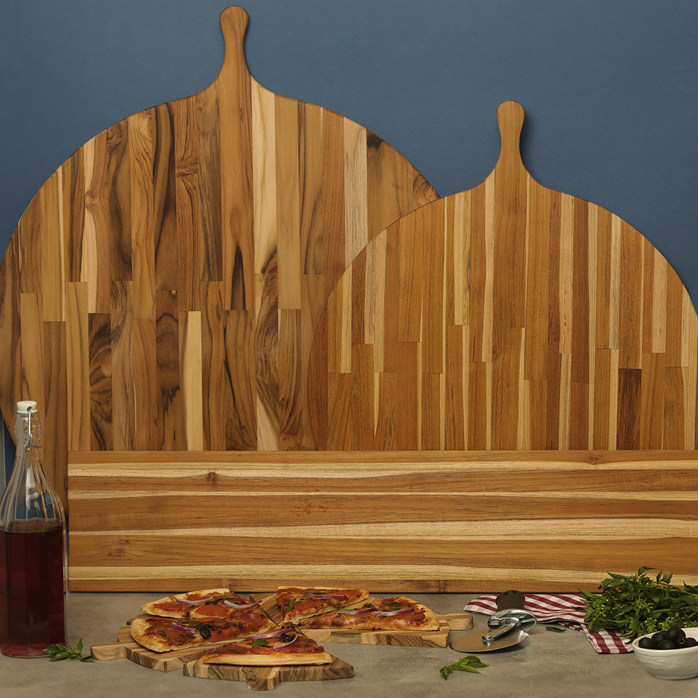 Sustainable teak wood pizza serving boards and triangular edge grain platters arranged with fresh slices.